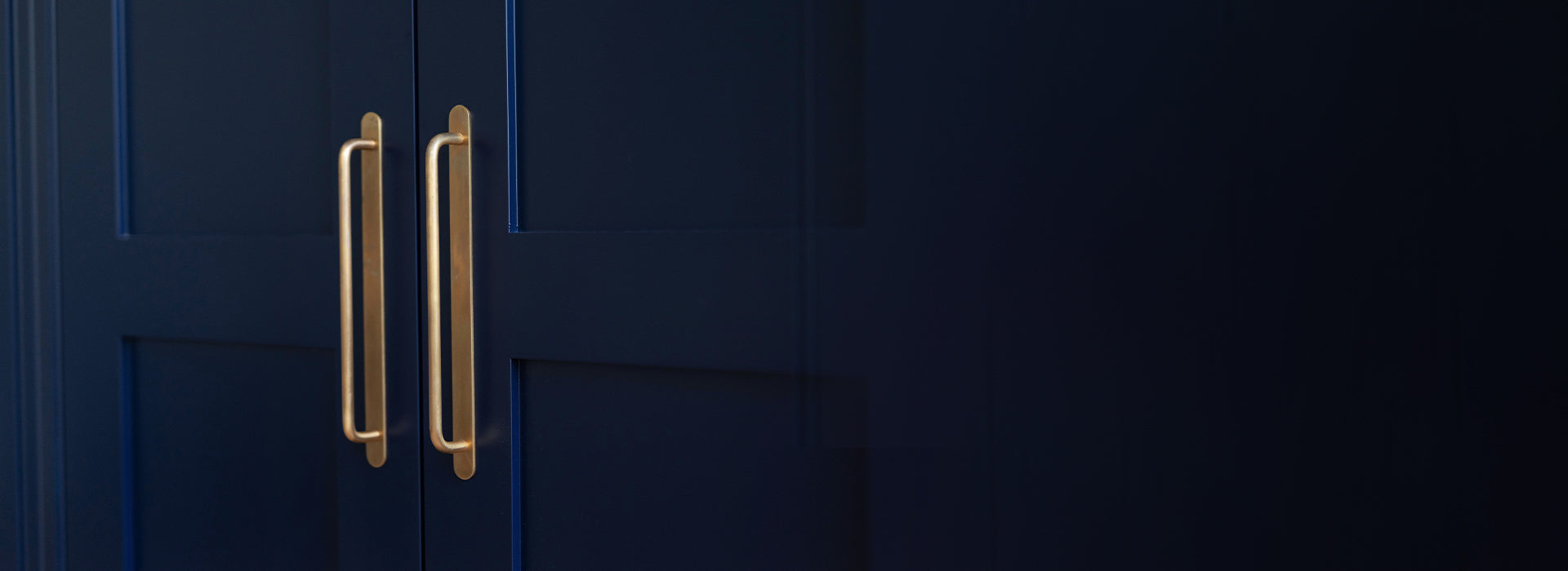 two antique brass poplar mortice door knobs on black doors