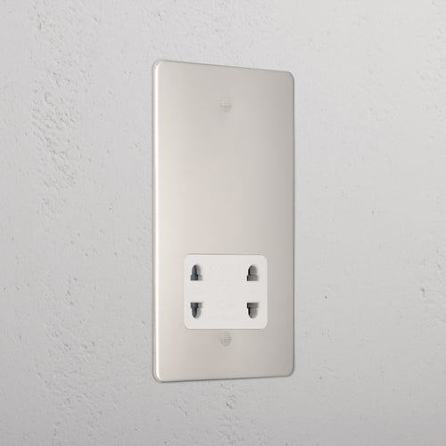 Polished nickel shaver socket with white insert on grey wall. 