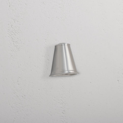 Southwark Mast Light – Polished Nickel, a small wall light with a sleek, conical design mounted on a white wall.