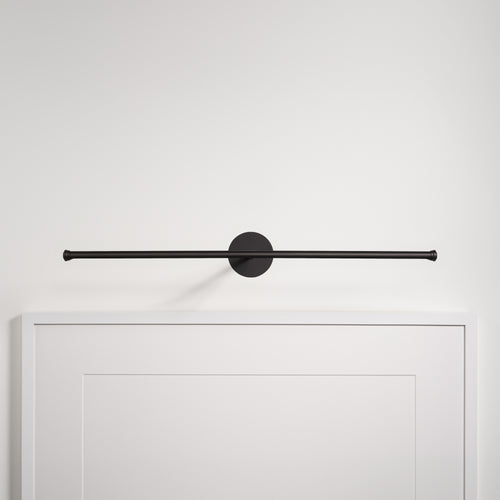 Bronze Taylor Picture Light 580mm, wall-mounted above a white frame on a white wall.